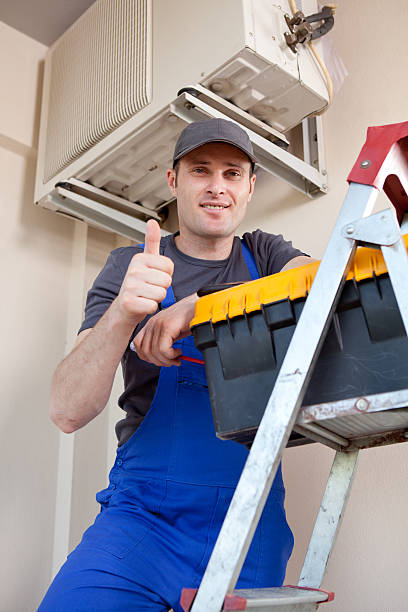 Ac Services Sharjah, Serviceman is smiling at camera with air conditioner.